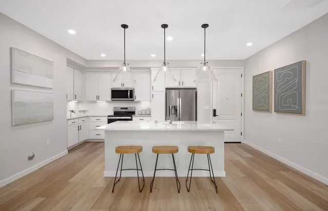 a kitchen with stainless steel appliances kitchen island granite countertop a stove a sink and a refrigerator with wooden floor