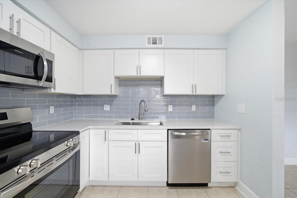 17035 Gulf Boulevard, Unit 118 North Redington Beach, FL 33708 - Photo 19 of 44 a kitchen with white cabinets stainless steel appliances and sink