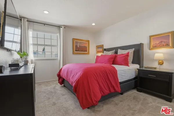 a bedroom with a bed and a flat tv screen on the dresser