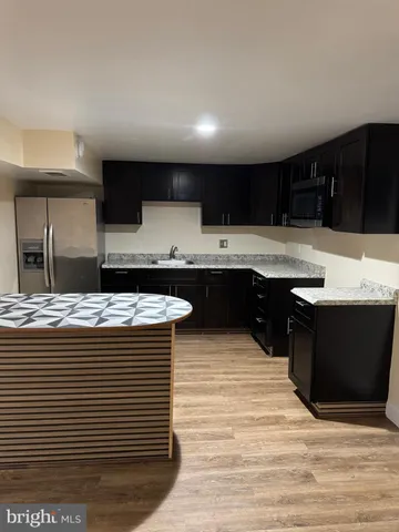 a kitchen with kitchen island stainless steel appliances a sink counter space and wooden floor