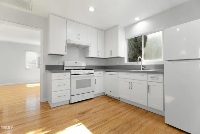 a kitchen with granite countertop white cabinets and white appliances