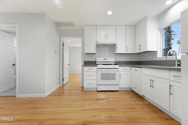 a kitchen with granite countertop white cabinets and white appliances
