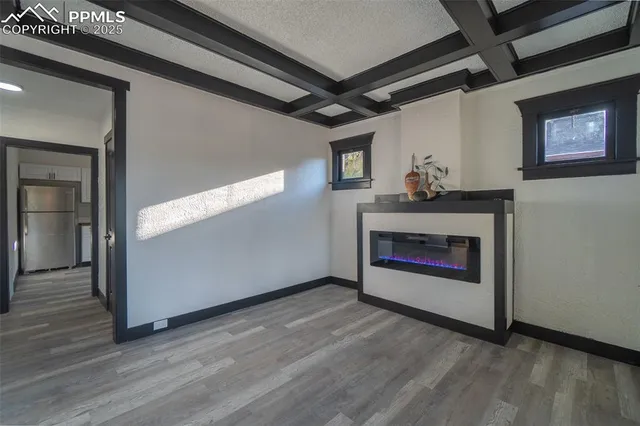 a view of an empty room with wooden floor and a fireplace