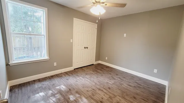 an empty room with wooden floor and windows