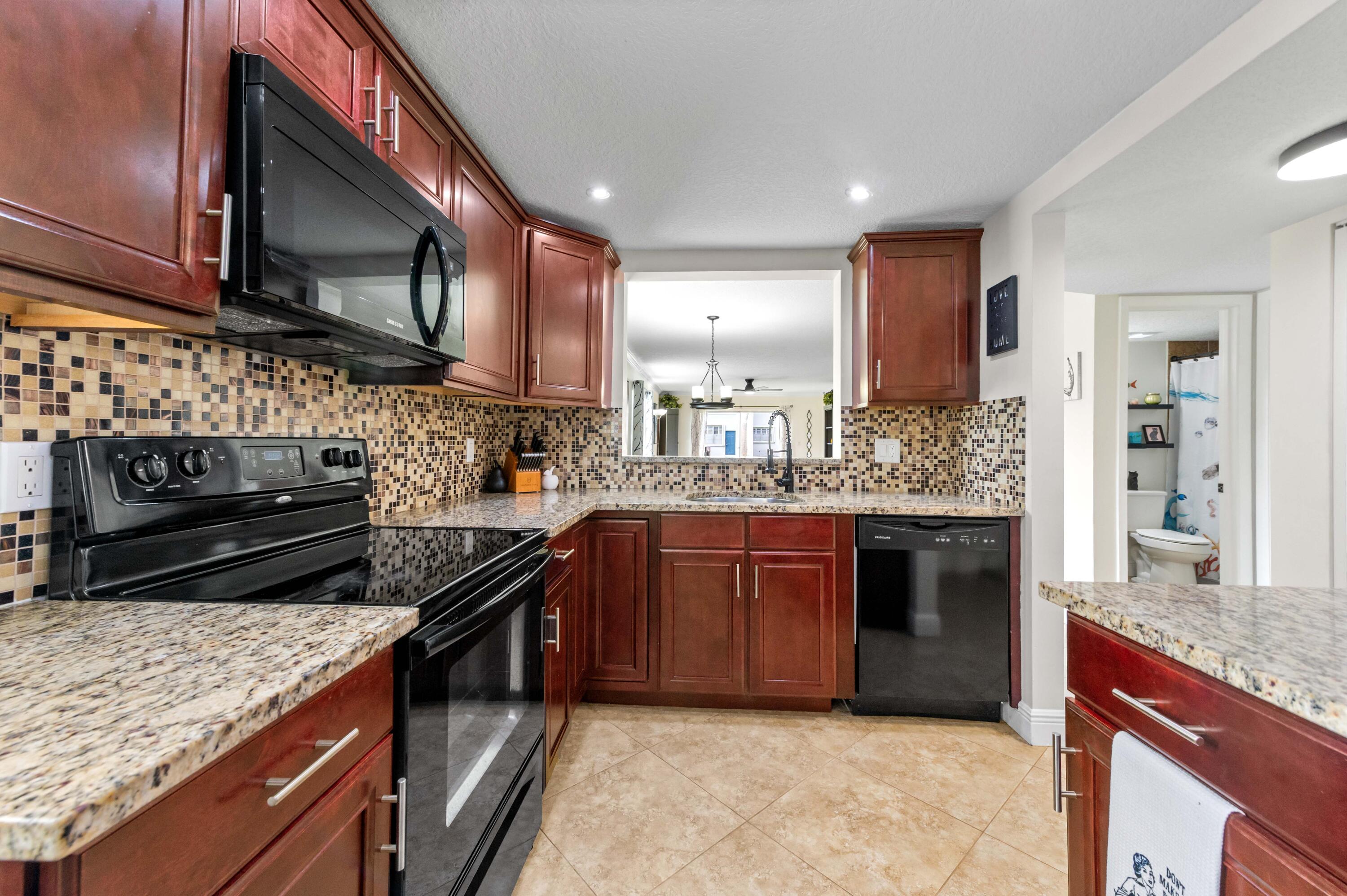 2905 Southwest 22nd Avenue, Unit 1080 Delray Beach, FL 33445 - Photo 11 of 33 a kitchen with stainless steel appliances granite countertop a stove microwave and sink
