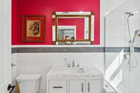 a bathroom with a granite countertop sink mirror vanity and toilet