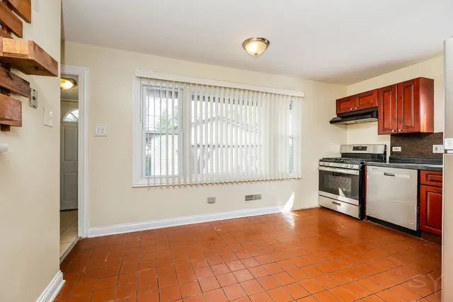 a view of an empty room with a window and kitchen view