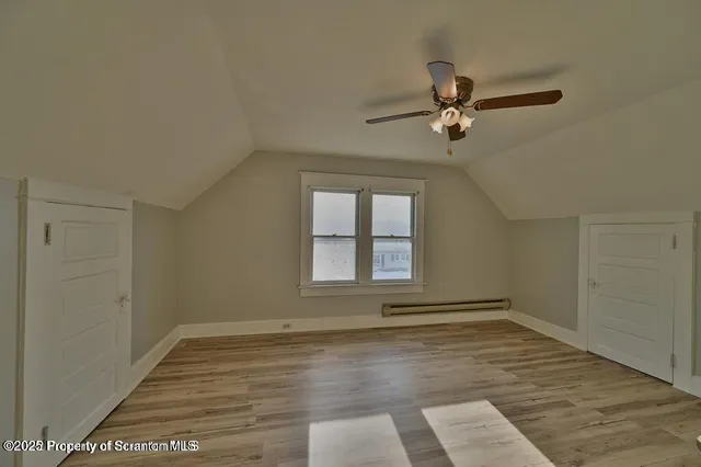 an empty room with wooden floor fan and windows
