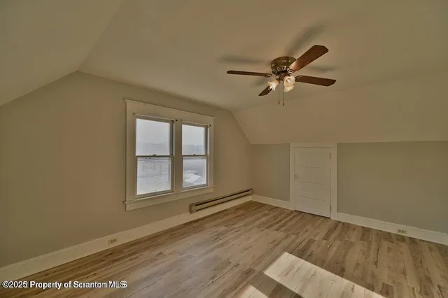 an empty room with wooden floor fan and windows