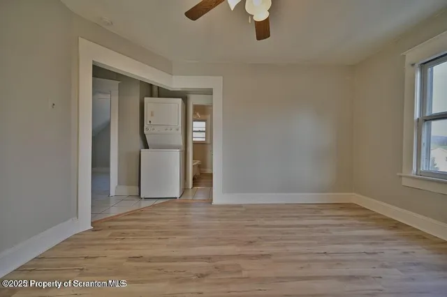 a view of an empty room with a window and wooden floor