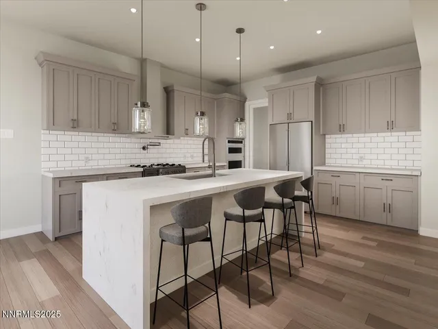 a kitchen with stainless steel appliances granite countertop a stove a sink a refrigerator and a dining table with wooden floor