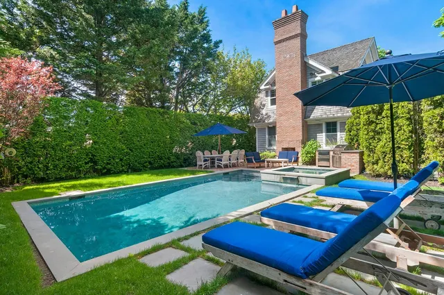 a view of a tennis ground with a table and chairs under an umbrella
