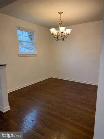a view of an empty room with wooden floor and chandelier