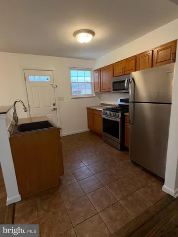 a kitchen with granite countertop a refrigerator and a stove top oven