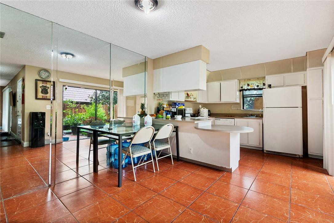 7543 Courtyard Run East, Unit 7543 Boca Raton, FL 33433 - Photo 4 of 15 a kitchen with a table chairs refrigerator and cabinets