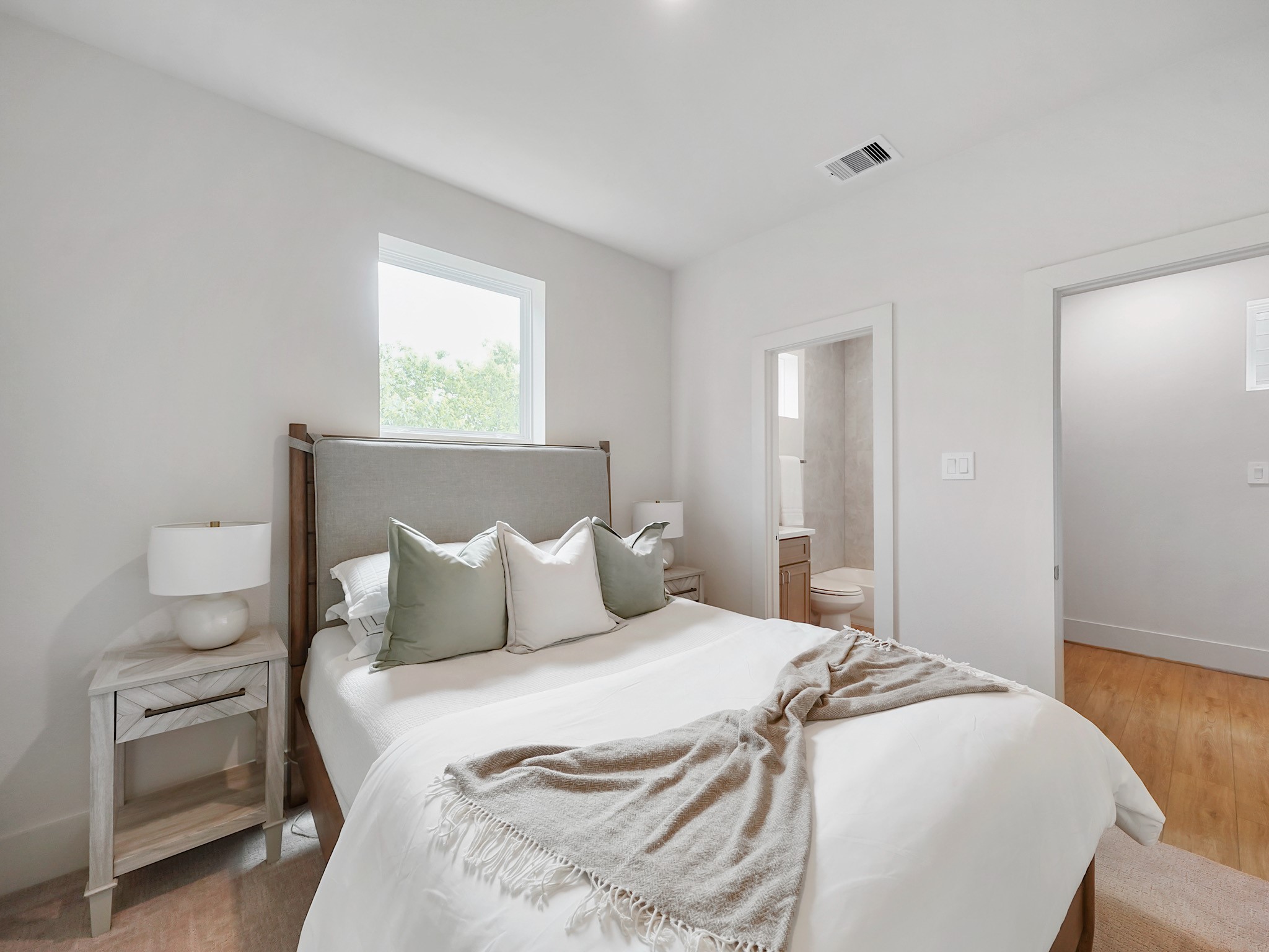 861 Rachel Street, Unit E Houston, TX 77091 - Photo 20 of 29 This inviting second bedroom features a bright, airy ambiance with a cozy bed, modern decor, and an en-suite bathroom, perfect for relaxation and comfort.