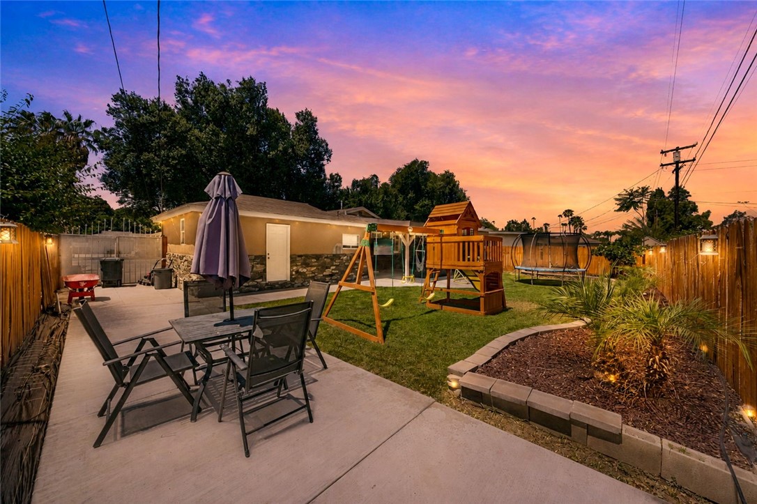 4869 Serrano Place Riverside, CA 92504 - Photo 4 of 40 Wonderful outdoor space with a large patio, play set, trampoline, and landscaped areas that feel bright and inviting.