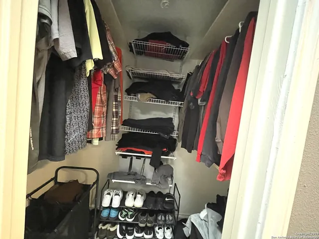a view of walk in closet with clothes and shoes