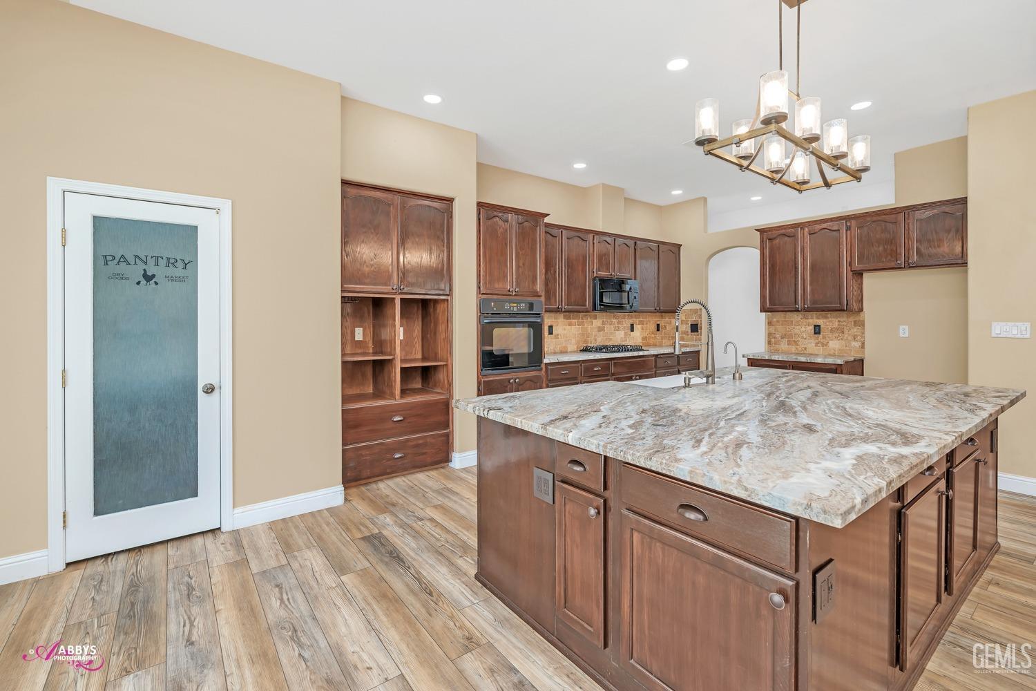 Undisclosed Address Bakersfield, CA 93311 - Photo 15 of 41 a kitchen with kitchen island granite countertop a sink refrigerator and cabinets
