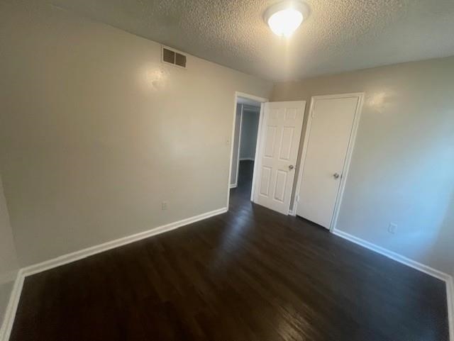 48 South Bristol Road Marion, AR 72364 - Photo 8 of 18 Unfurnished bedroom with dark wood finished floors, a textured ceiling, and a closet
