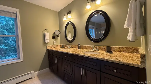 a bathroom with a granite countertop double vanity sink and a mirror