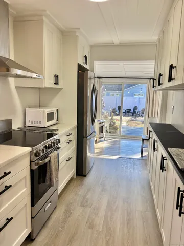 a large kitchen with stainless steel appliances granite countertop a lot of counter space and wooden floors