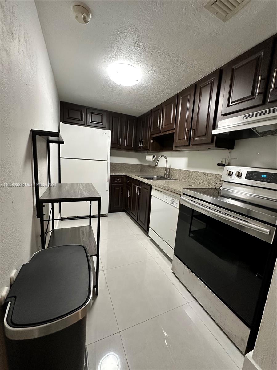 8794 Southwest 12th Street, Unit 108 Miami, FL 33174 - Photo 4 of 7 a kitchen with stainless steel appliances granite countertop a stove a sink and a microwave