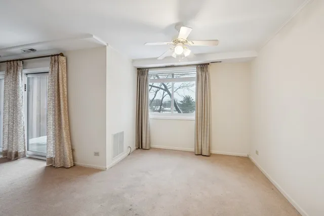 an empty room with windows and fan