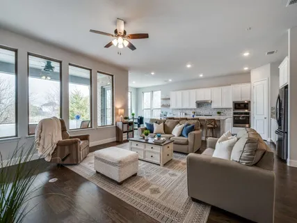 a living room with furniture kitchen area and a large window