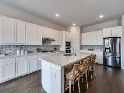 a kitchen with stainless steel appliances granite countertop a table chairs sink refrigerator and microwave