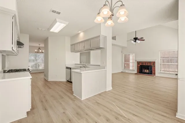 a open kitchen with a refrigerator a stove top oven a chimney and wooden floor