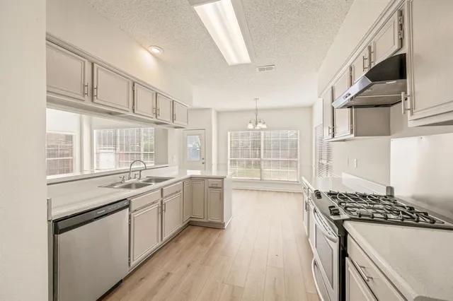 a kitchen with granite countertop a sink stove and cabinets