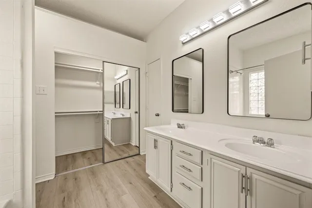 a spacious bathroom with a double vanity sink a mirror and a shower