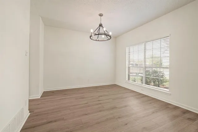 an empty room with wooden floor fan and window