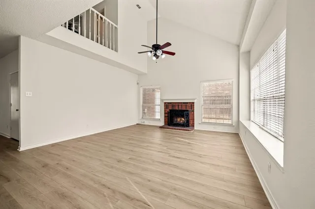 an empty room with windows fireplace and a wooden floor
