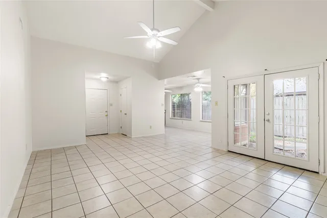 a view of an empty room with window and chandelier fan