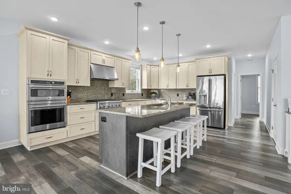 a kitchen with stainless steel appliances granite countertop a kitchen island a stove and a wooden floors