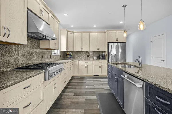 a kitchen with stainless steel appliances granite countertop hardwood floor sink stove and wooden cabinets