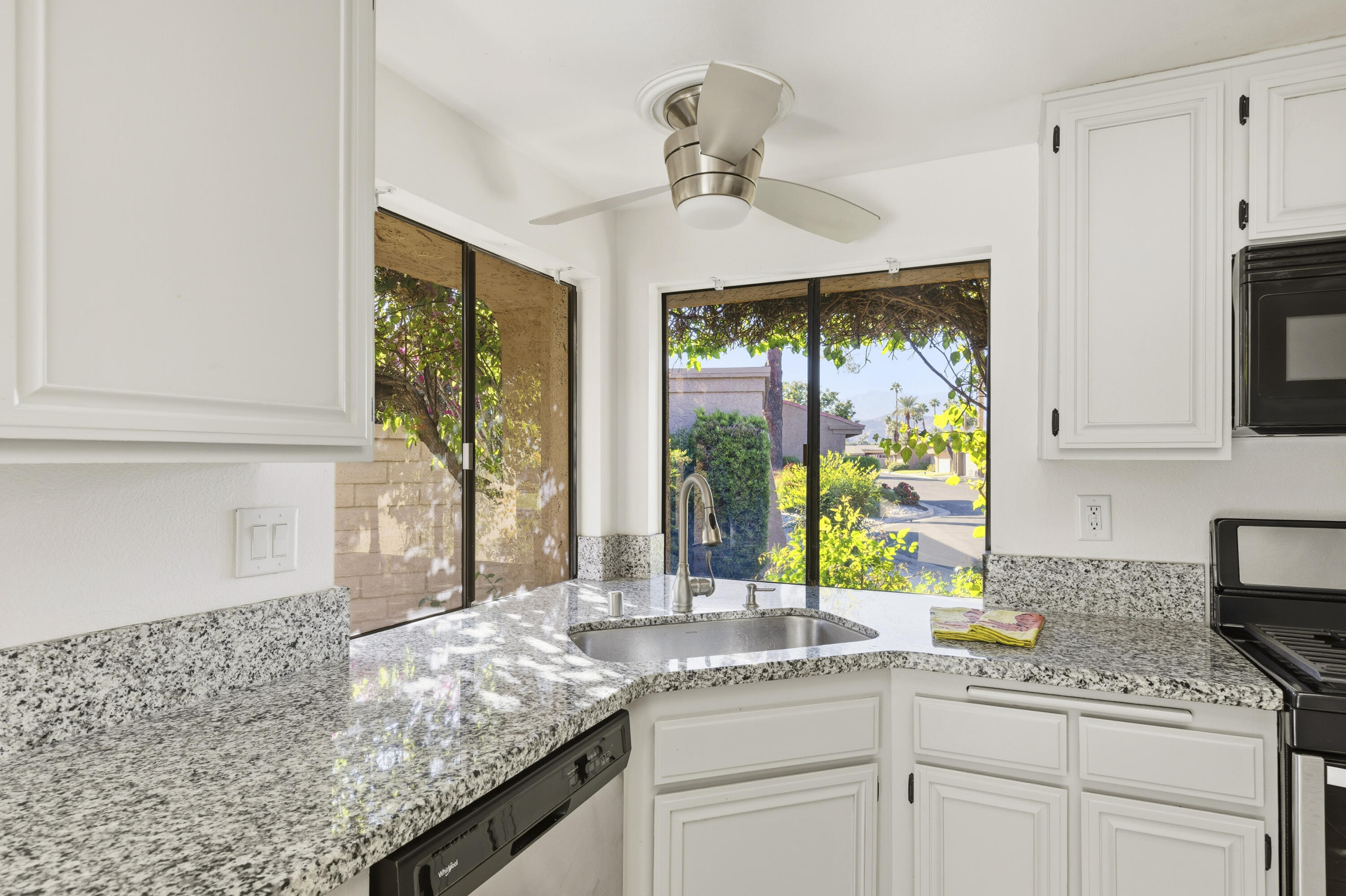 44695 Monaco Circle Palm Desert, CA 92260 - Photo 17 of 58 a kitchen with kitchen island granite countertop white cabinets and window