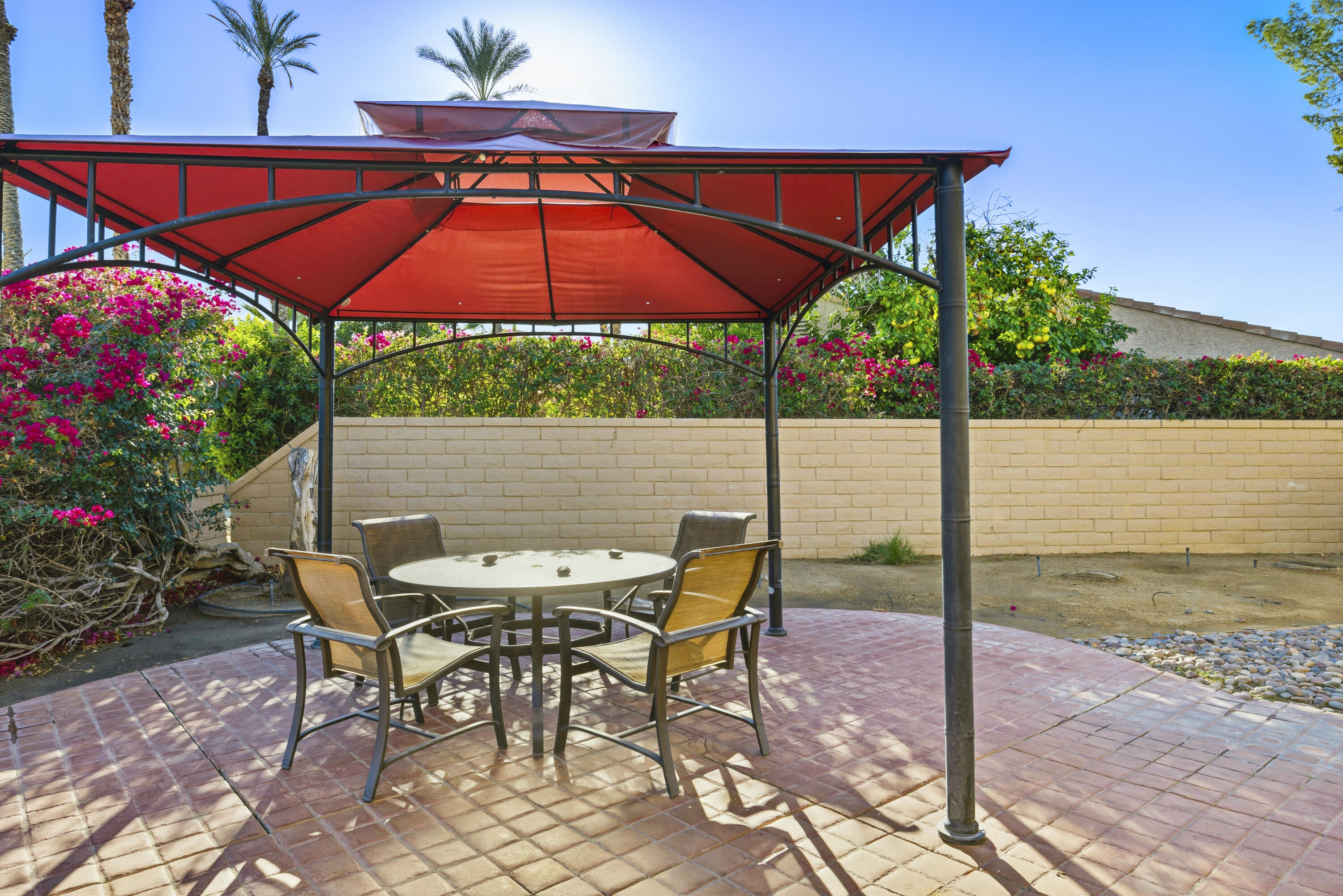 44695 Monaco Circle Palm Desert, CA 92260 - Photo 33 of 58 a patio with a table and chairs under an umbrella