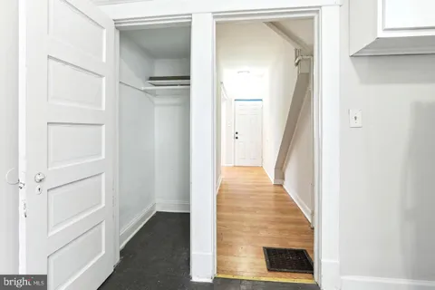 a view of a hallway with wooden floor and a bathroom