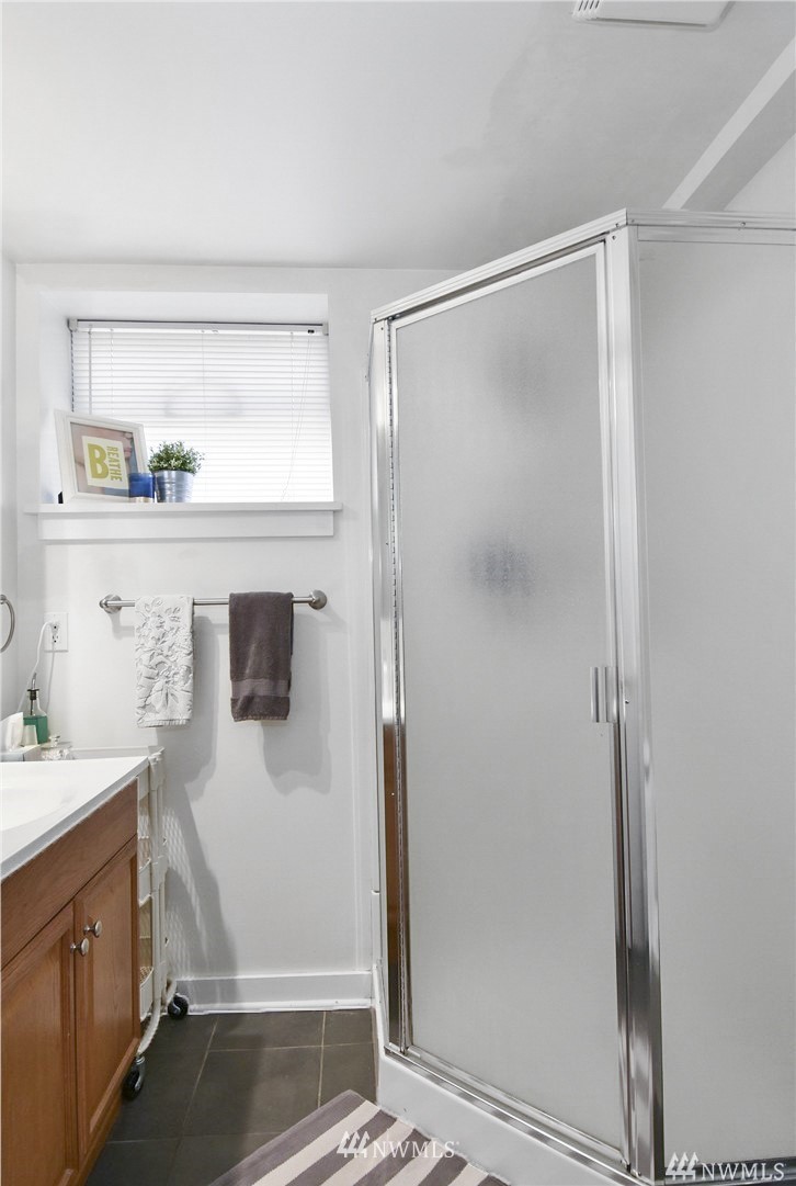 1706 North 50th Street Seattle, WA 98103 - Photo 15 of 18 a bathroom with a shower sink and mirror