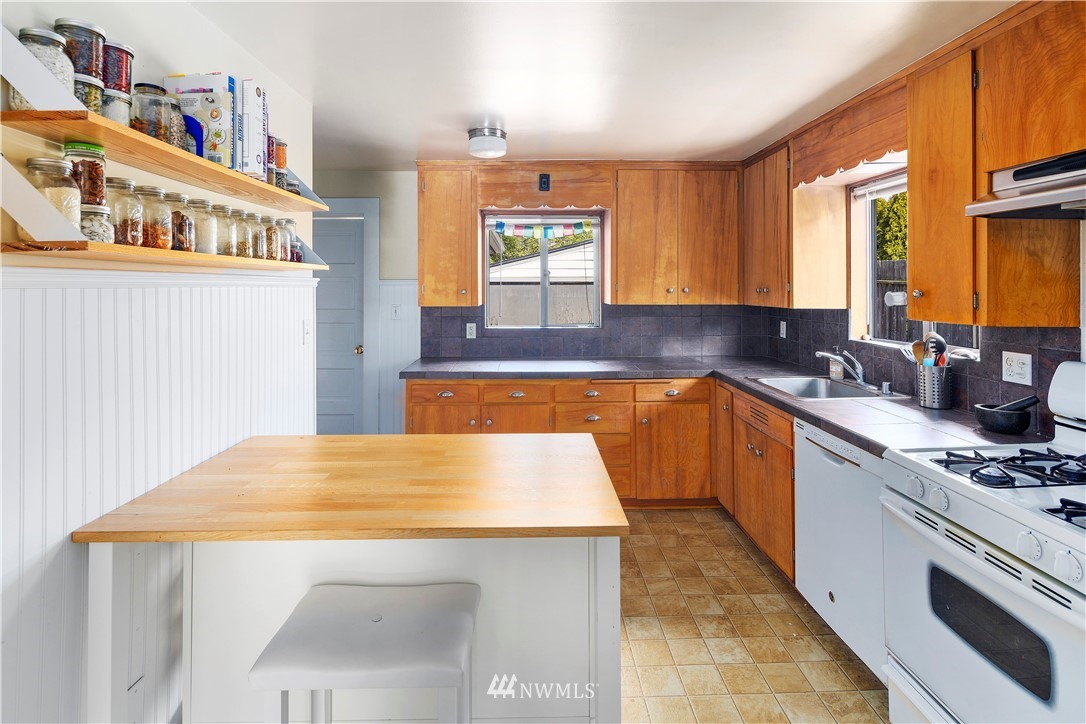 1706 North 50th Street Seattle, WA 98103 - Photo 4 of 18 a kitchen with stainless steel appliances kitchen island granite countertop a sink a stove top oven a counter space and cabinets