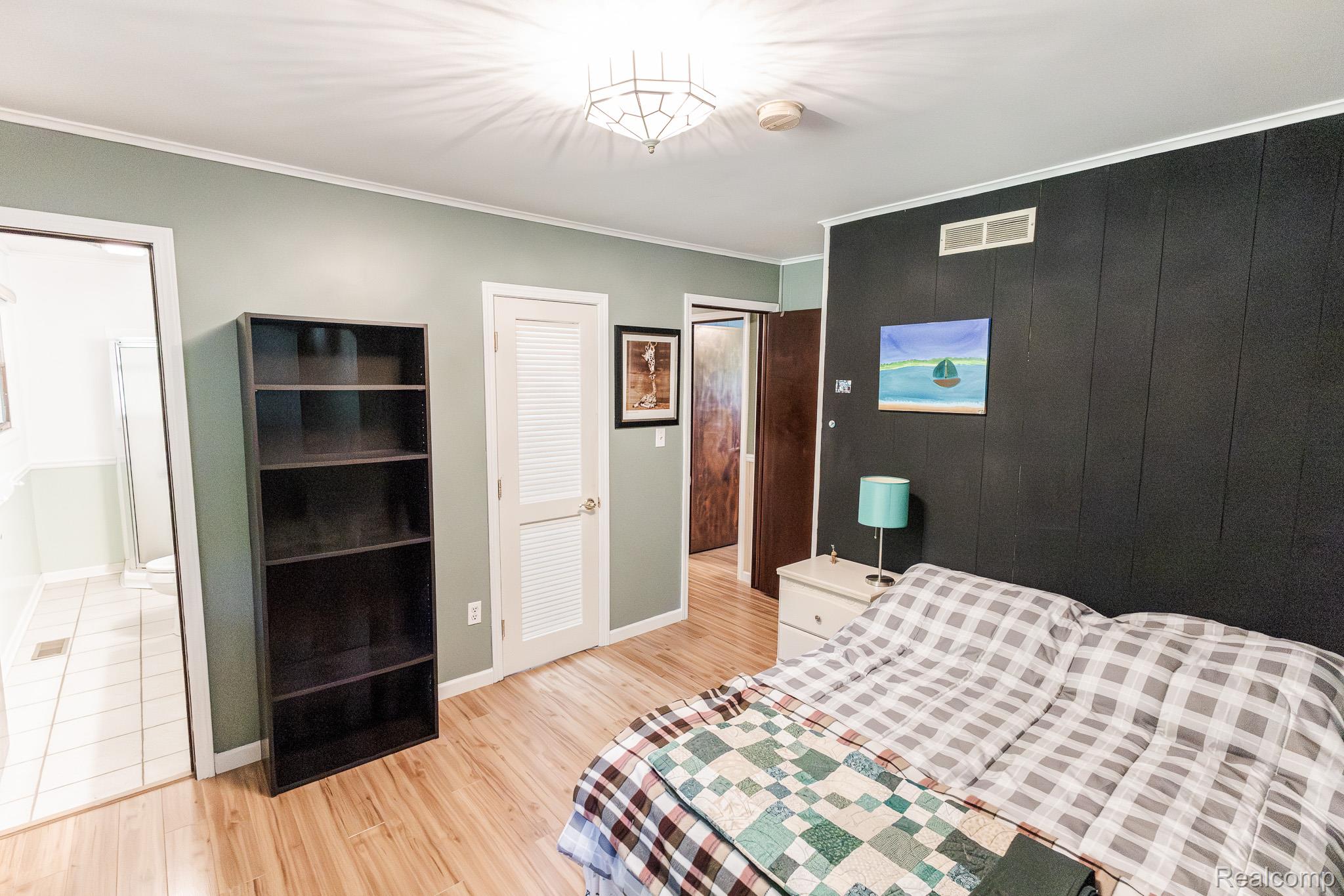 8197 Irish Road Millington, MI 48746 - Photo 24 of 38 Bedroom featuring wood-finish flooring, a textured black accent wall, and a ceiling-mounted light fixture