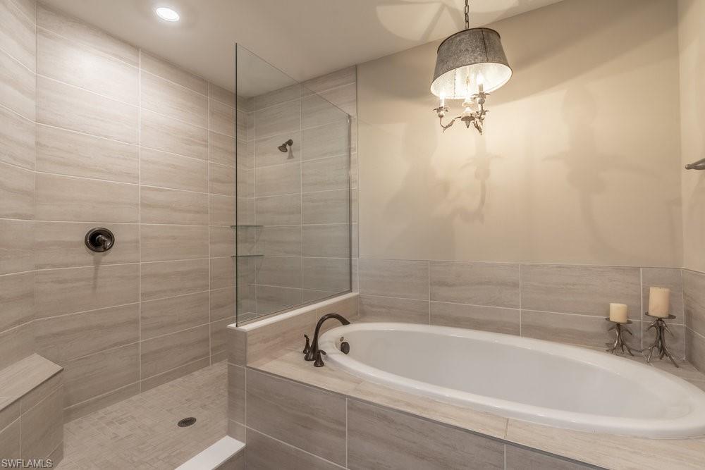 16375 Viansa Way, Unit 102 Naples, FL 34110 - Photo 24 of 40 a white bath tub sitting next to a white sink and a shower