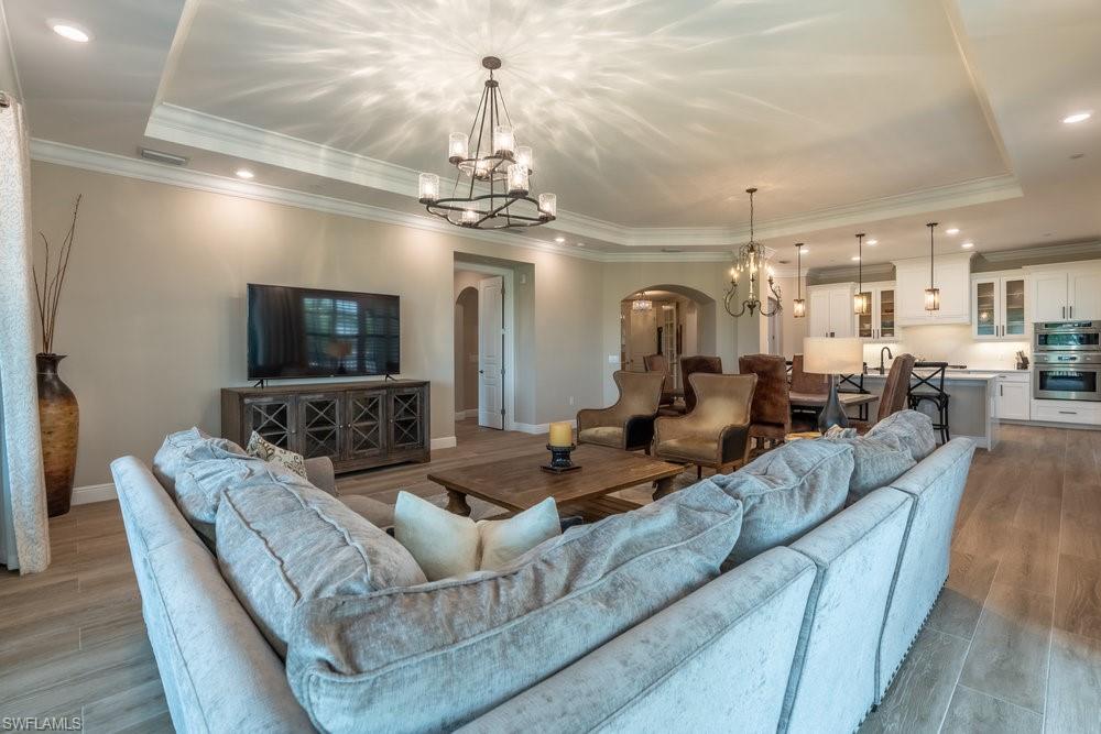 16375 Viansa Way, Unit 102 Naples, FL 34110 - Photo 7 of 40 a living room with furniture a chandelier and a flat screen tv