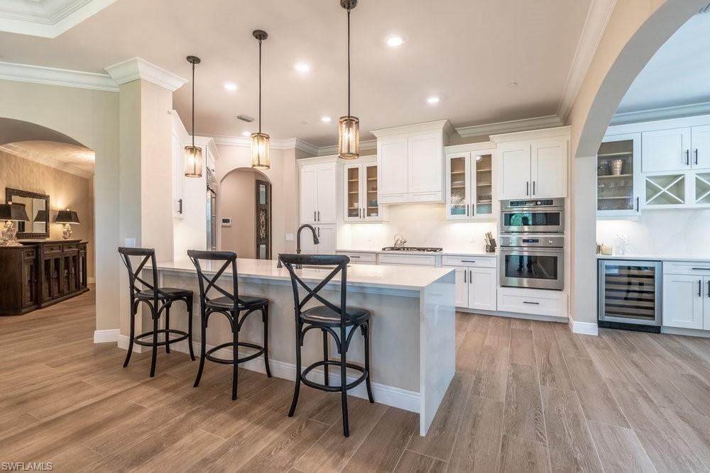 16375 Viansa Way, Unit 102 Naples, FL 34110 - Photo 9 of 40 a kitchen with stainless steel appliances kitchen island granite countertop a table chairs stove a sink dishwasher and cabinets with wooden floor