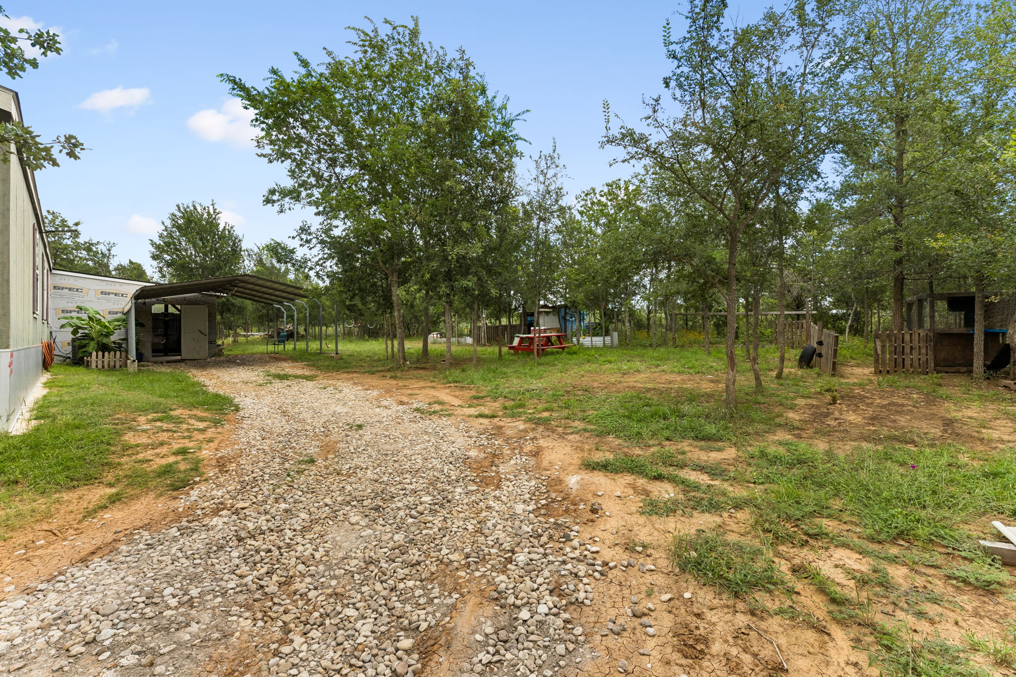 253 North County Line Road, Unit C Elgin, TX 78621 - Photo 25 of 39 A long gravel drive leads to a spacious property with mature trees and a versatile carport.