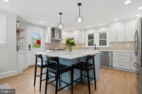 a kitchen with stainless steel appliances kitchen island granite countertop a dining table chairs and white cabinets