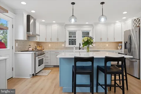 a kitchen with refrigerator a sink and chairs